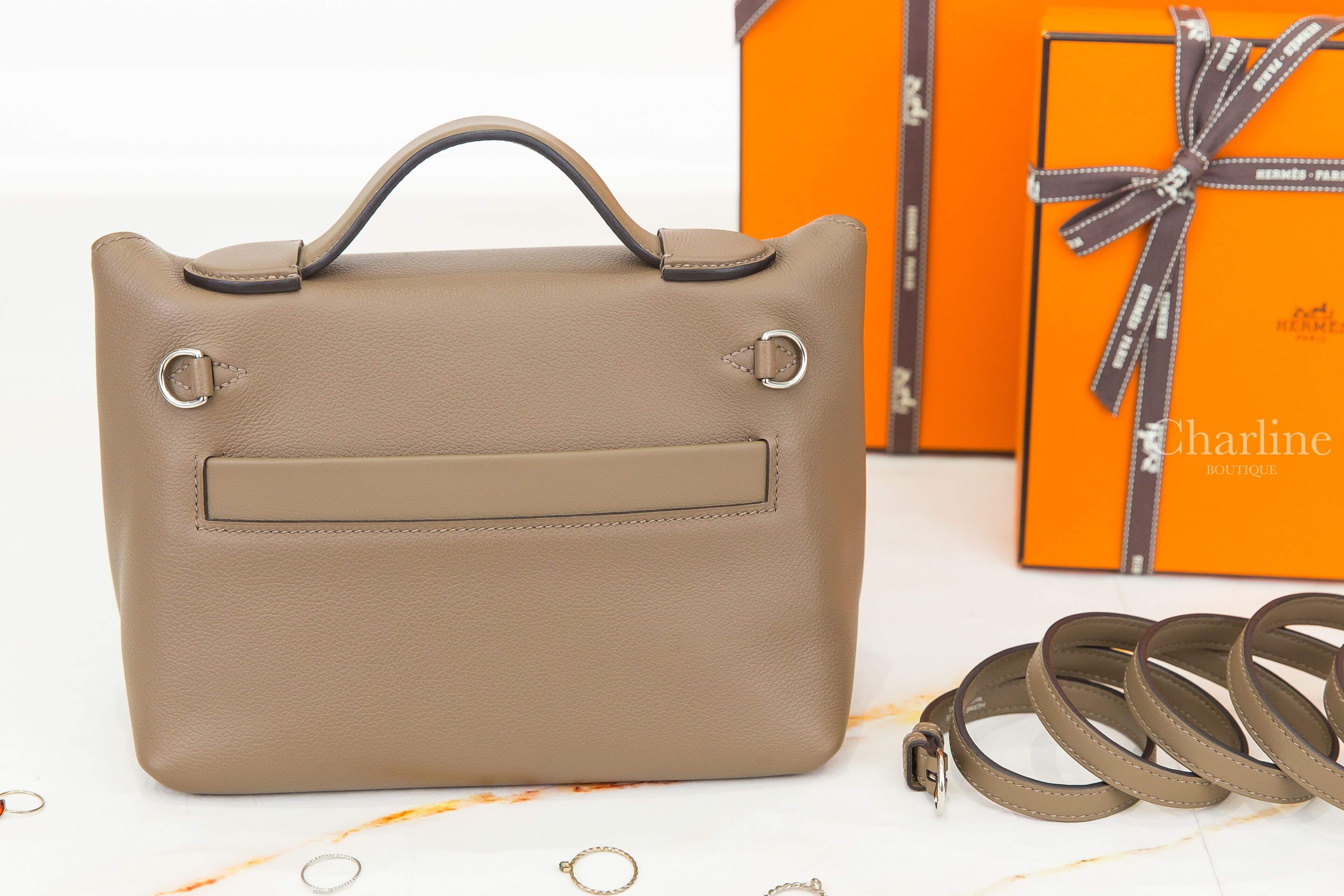 Hermès Mini Kelly 2 Etoupe 大象灰手提肩背包背面展示，呈現背面平口口袋、左右銀色肩帶扣環、弧形提把及細緻皮革紋理。