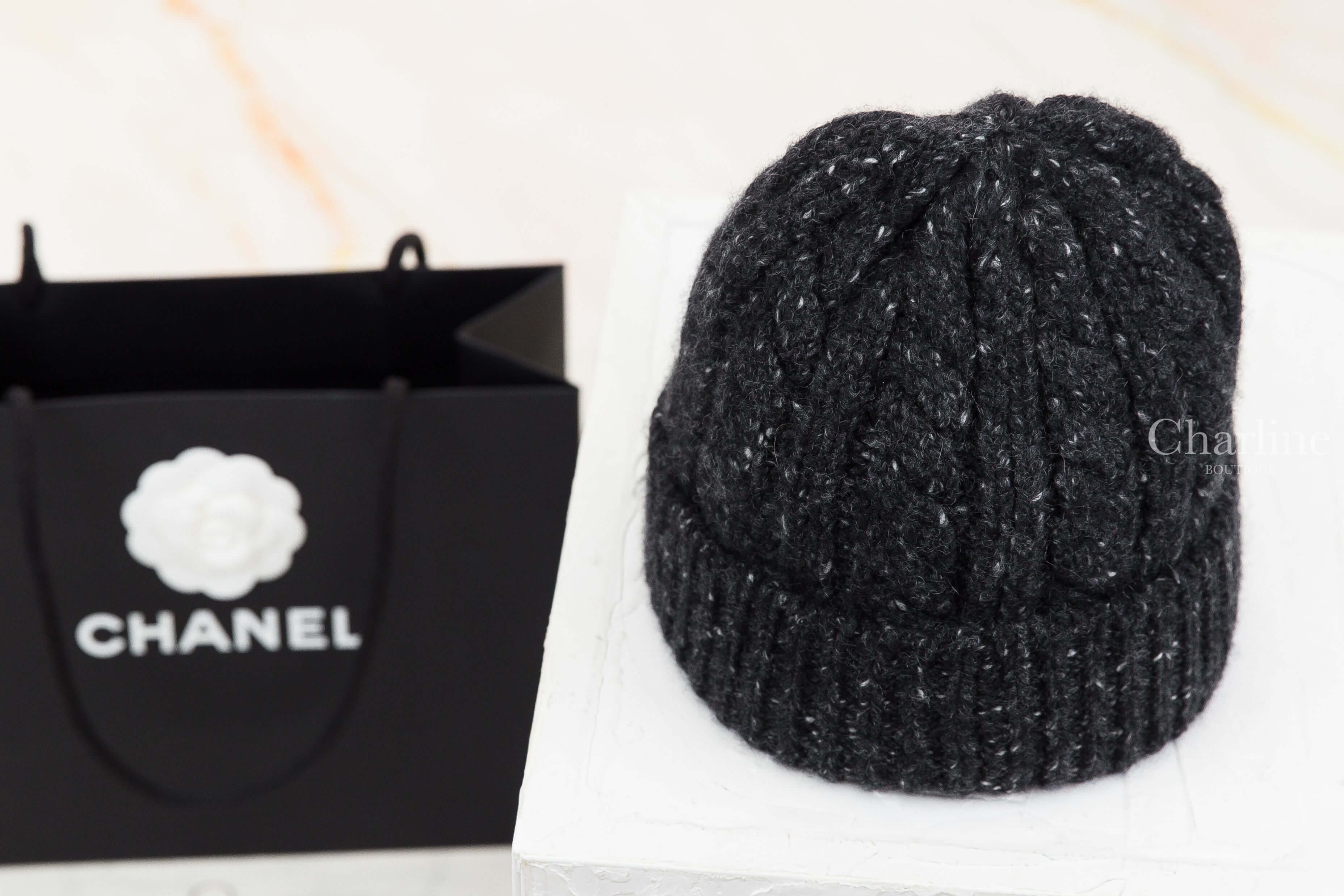 CHANEL 香奈兒黑色喀什米爾針織毛帽背面展示，呈現帽身立體羅紋編織、帽頂收針線條與反摺帽沿設計，黑色紗線交織細緻白色纖維。