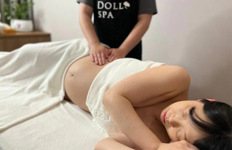 逗DOLLSPA孕婦按摩,按摩師為側躺的孕婦進行孕期腰背按摩。