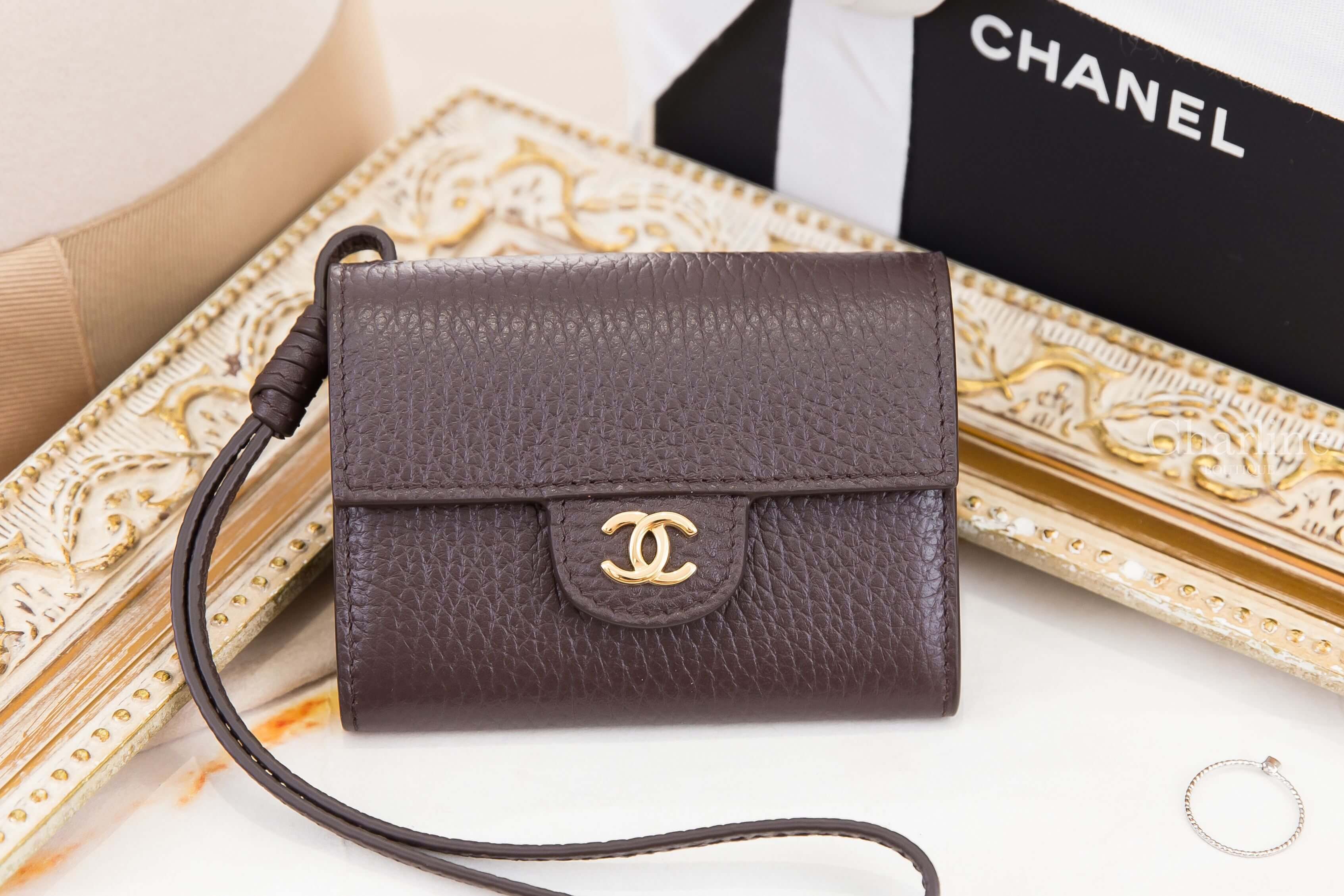 Chanel Mini Bag Charm 深棕色粒紋小牛皮卡片零錢夾正面展示，金色CC標誌搭配皮革腕帶