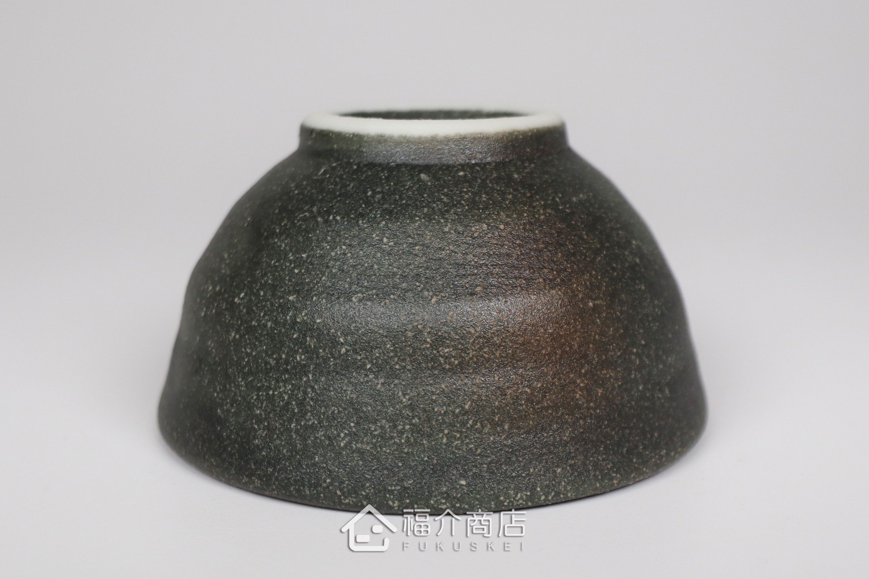 備前手作陶杯以沉穩洗鍊的黑陶質地為底蘊，表面散發著如星芒微閃般的細緻砂質顆粒，為餐桌與品飲時光增添一份低調靜謐的侘寂美學。