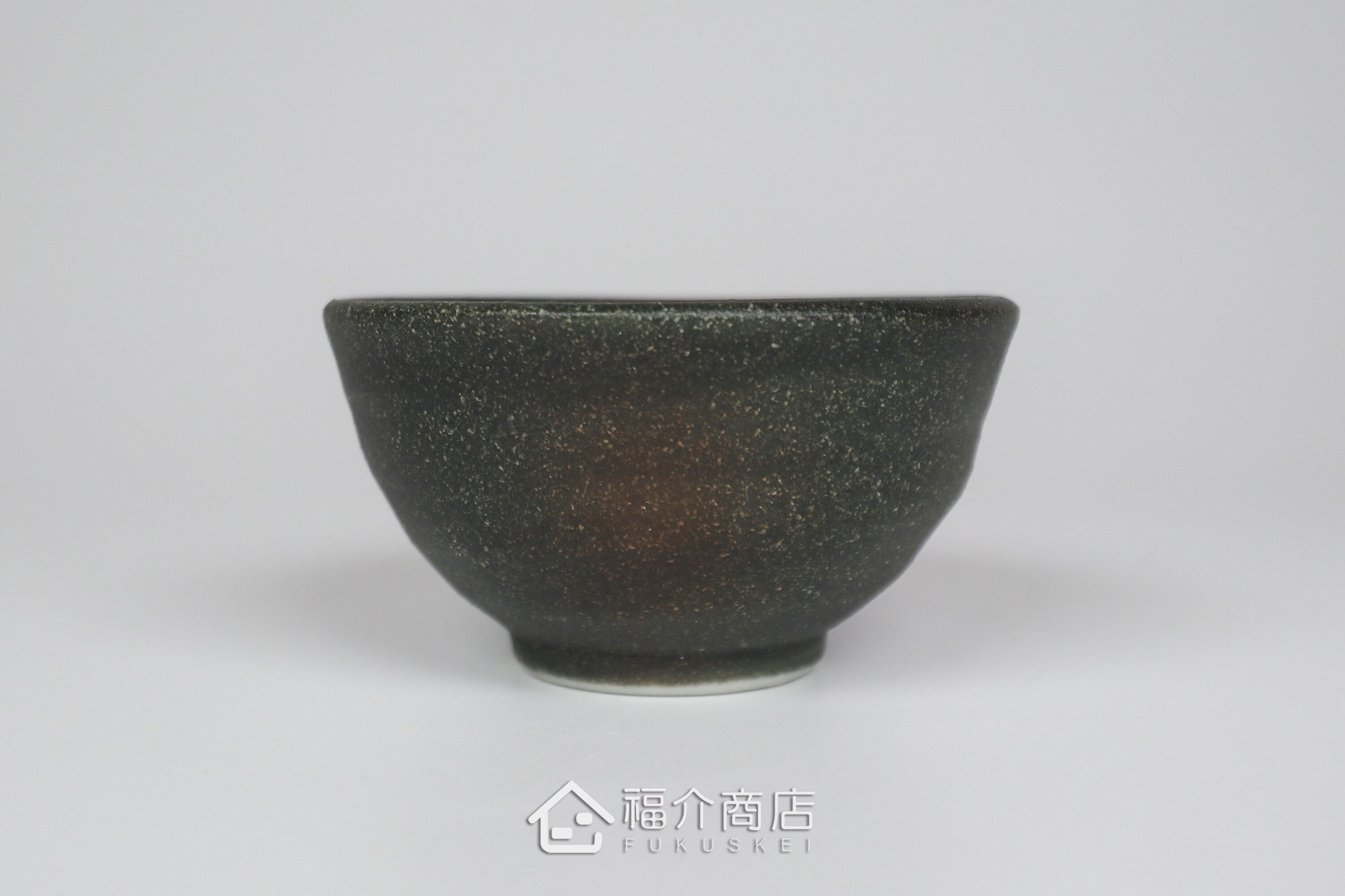 備前手作陶杯以沉穩洗鍊的黑陶質地為底蘊，表面散發著如星芒微閃般的細緻砂質顆粒，為餐桌與品飲時光增添一份低調靜謐的侘寂美學。