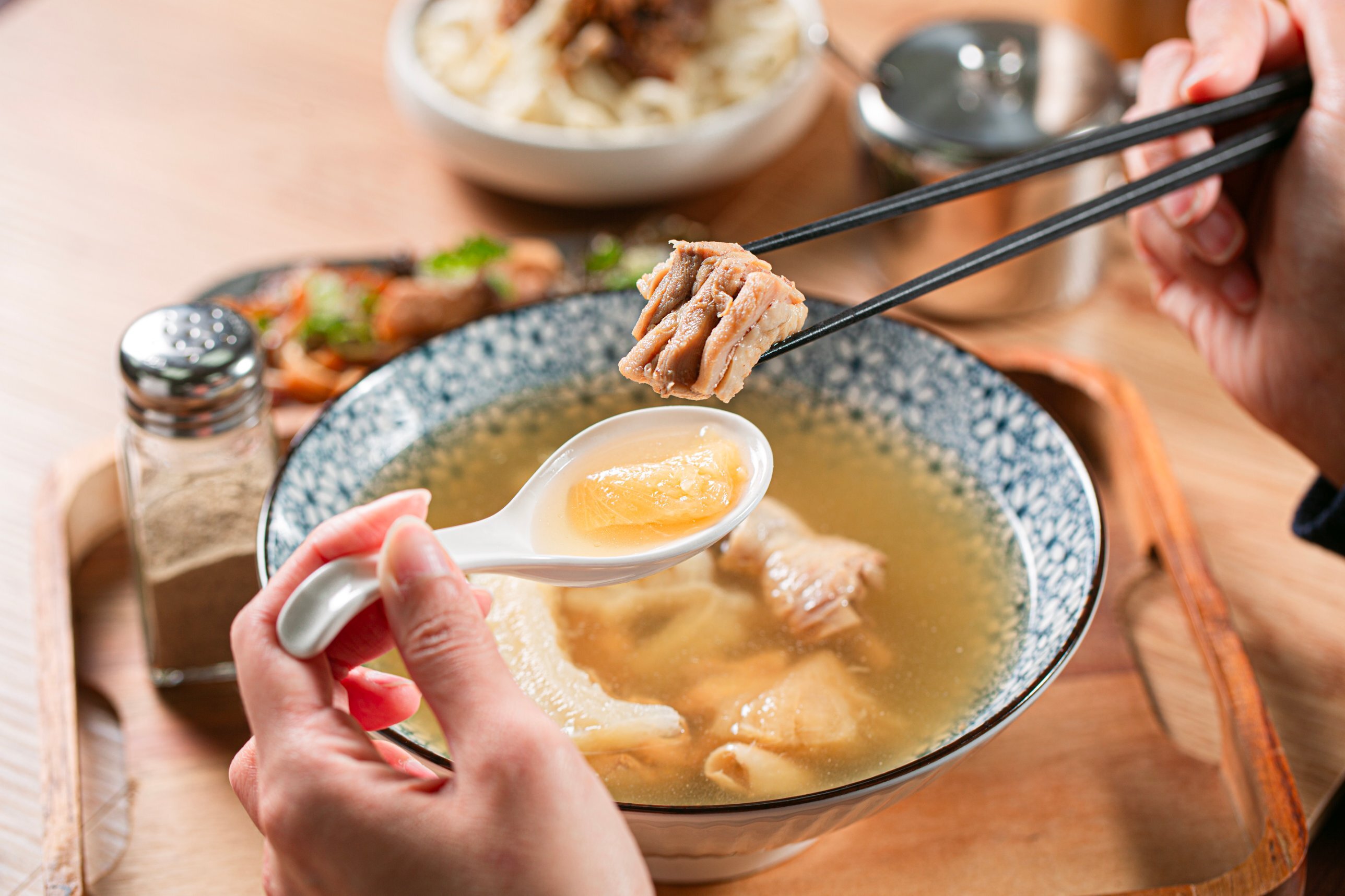 筷子夾起春水良品鳳梨苦瓜雞湯的雞肉,湯匙裡是燉透的苦瓜,湯頭金黃